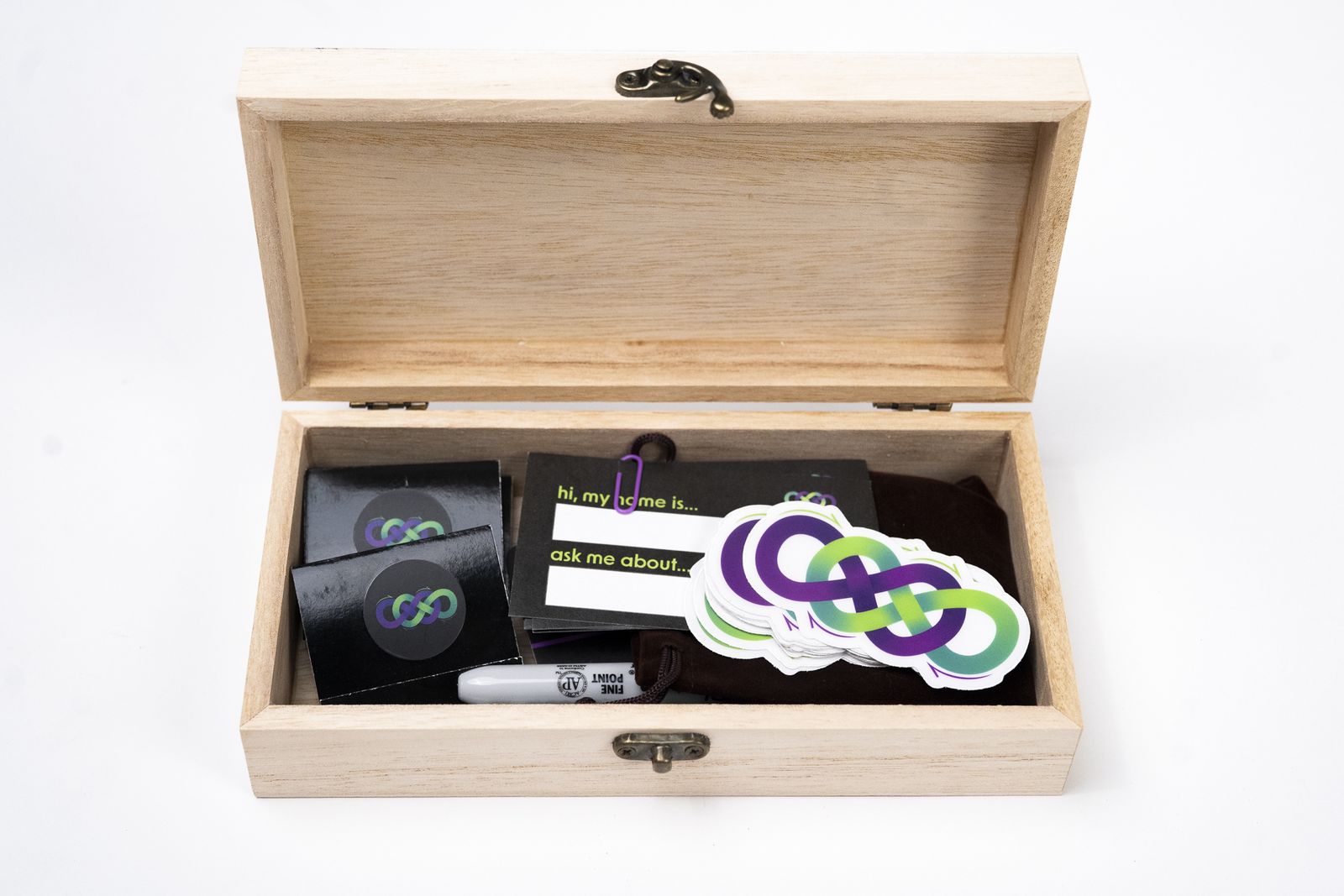 The wooden box of consumables: name tags, a velvet bag of mints, stickers, and a marker.